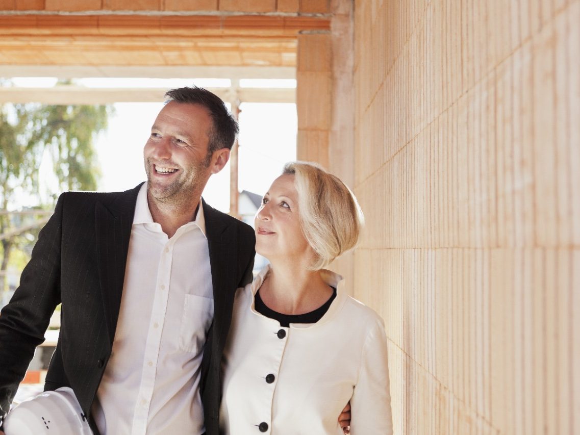 Happy couple inside unfinished building surrounded by bare brickwork