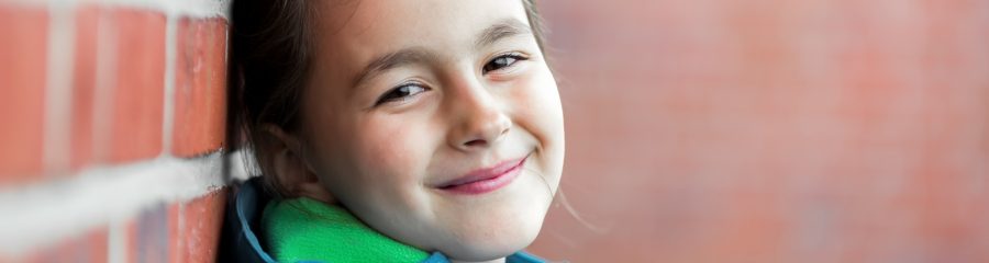 Tyttö nojaa tiiliseinään